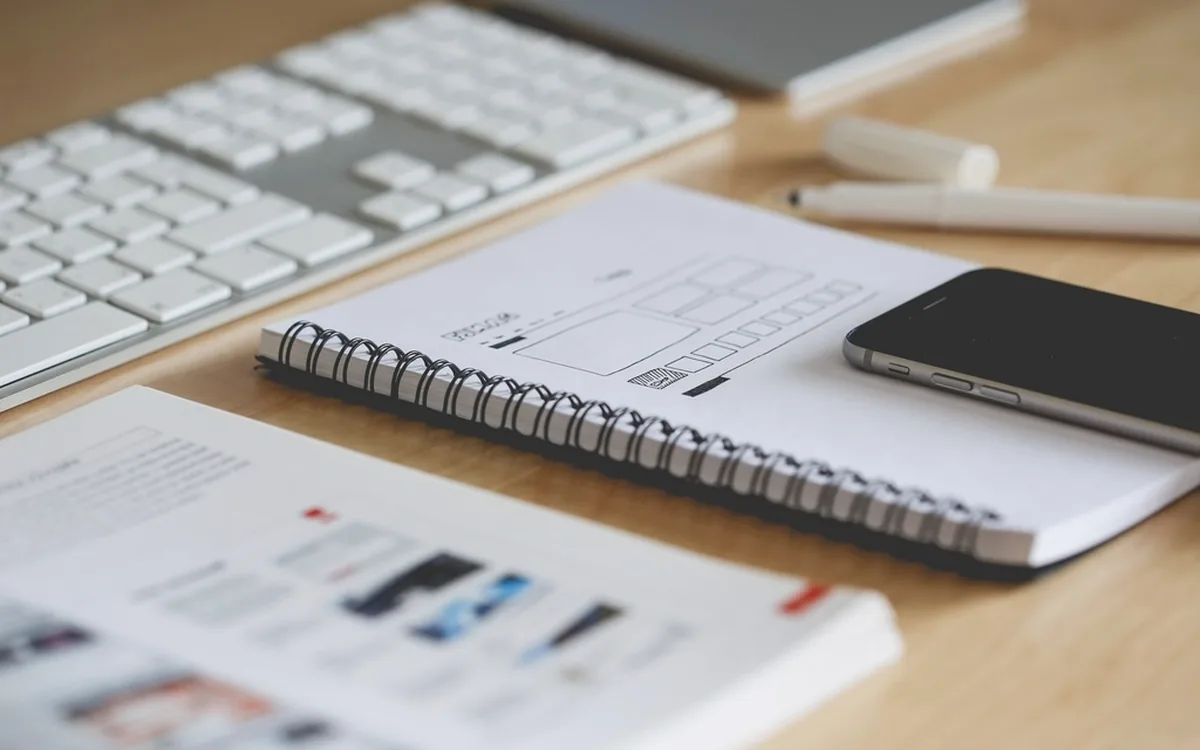 Schets van een paginaindeling naast een laptop op een werktafel
