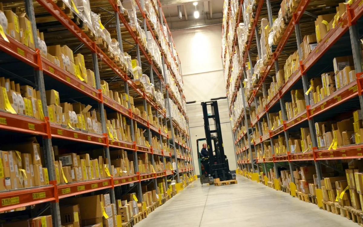 Heftruck in een gangpad tussen magazijnstellingen