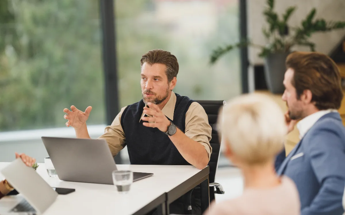 Overleg met drie mensen aan een vergadertafel